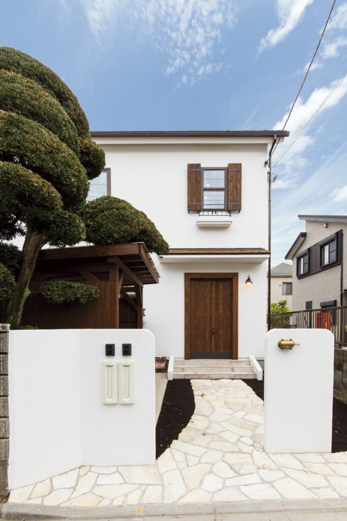 白い外壁に木製の玄関ドアとブラウンの窓飾りを合わせた、すっきりとした住まいです。 素材の色をアクセントにしながら、長く飽きのこないシンプルな外観に仕上げました。